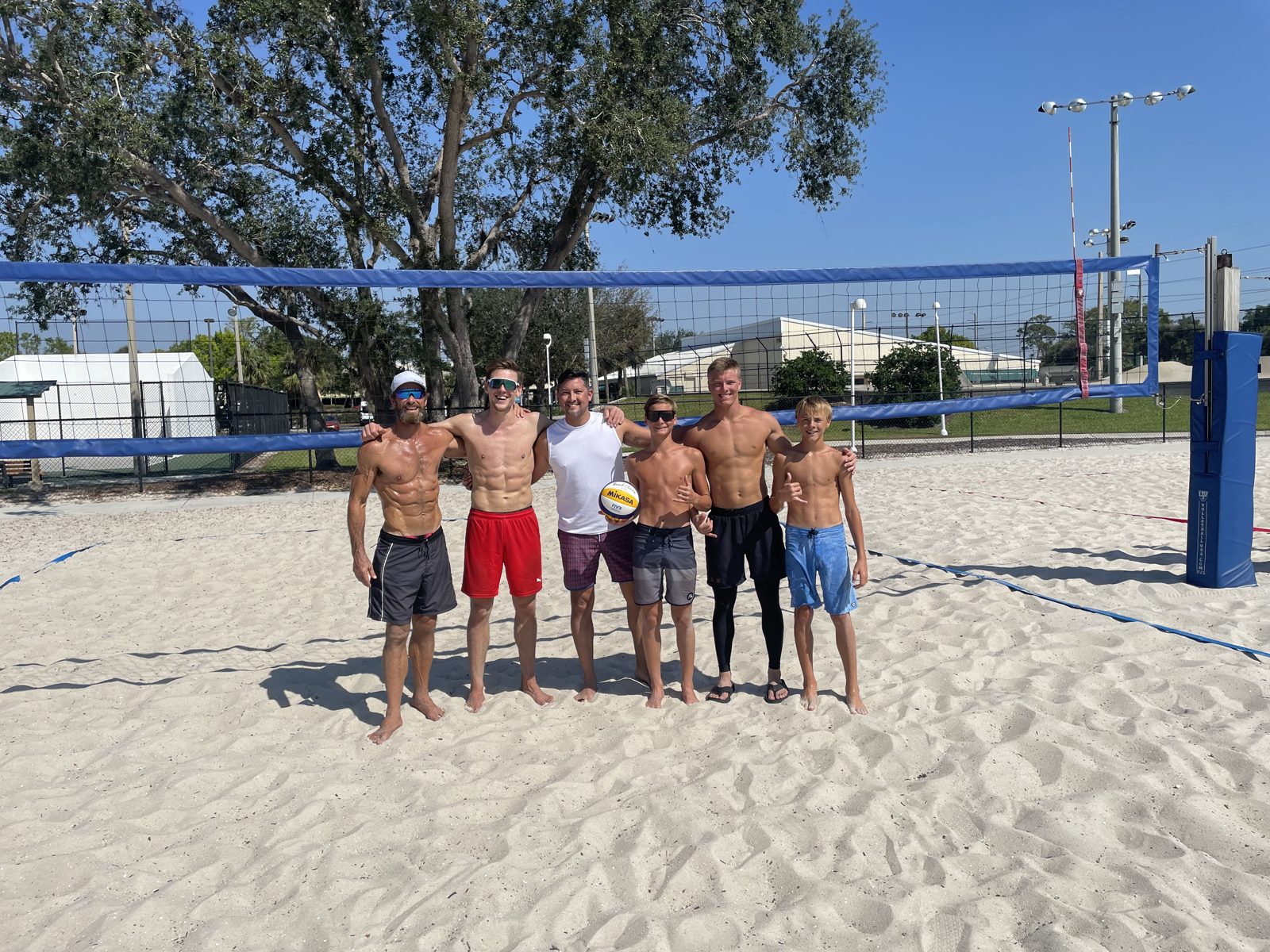 A group of players together on the court after a beach volleyball event