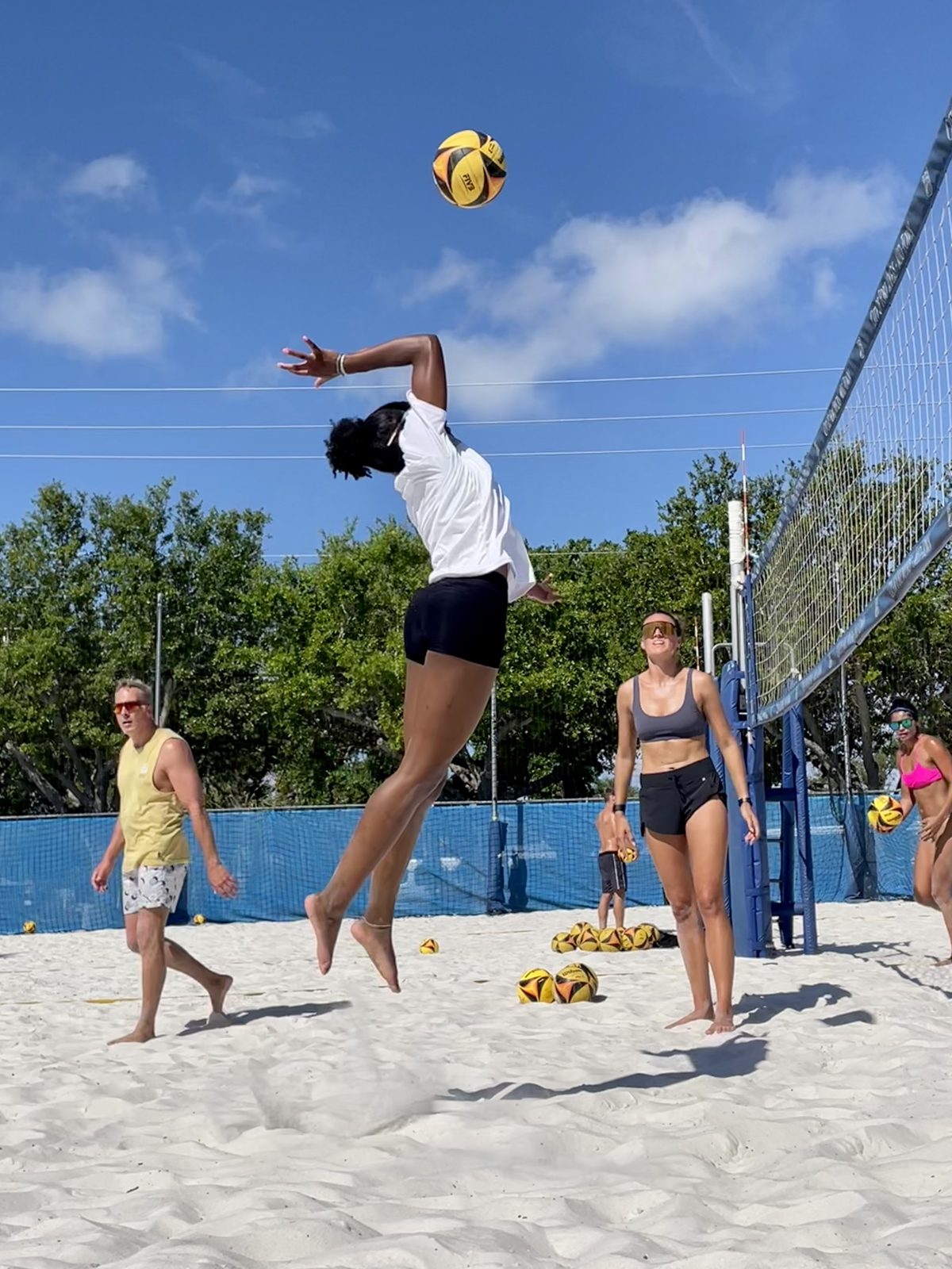 Junior athlete jumping to attack during beach volleyball training